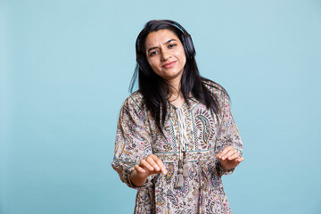 Happy woman playing electronic music and waving hand in the air, doing groovy dance moves in the...