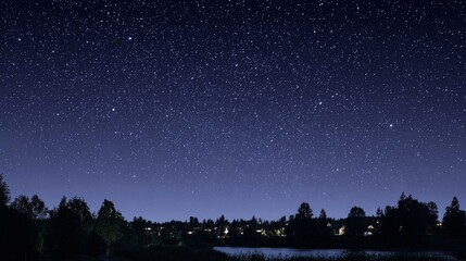 Night sky with stars above trees and water reflecting light.