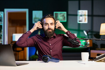 Content creator in neon lit apartment filming wireless headphones review for online streaming...
