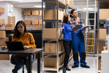 Asian team of workers in a depot checking the packages for shipment logistics, overseeing express...