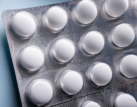 a close up view of a silver blister pack containing multiple round white pills possibly levocetirizine hydrochloride montelukast sodium or blister tablet packaging arranged in neat rows against