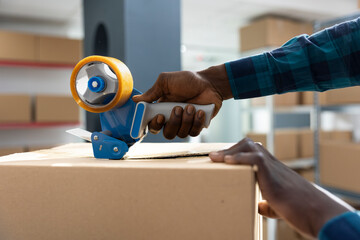 Factory worker applies adhesive tape to boxes while attaching air waybill and tracking numbers....