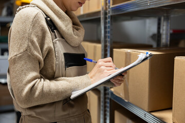 Industrial warehouse scene with employee counting merchandise to dispatch parcels. Shelving units...