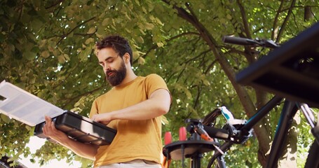 Motivated caucasian man diligently organizing specialized equipment from toolbox for bike...