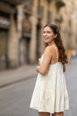 Young woman in dress walking on city street on summer day