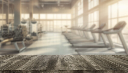 Rustic wooden worktop or tabletop with blurred background of a modern gym featuring treadmills and fitness equipment. Perfect for fitness mockups.