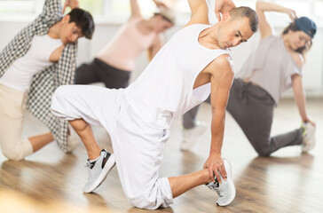 Man conducts training course for aspiring hip hop and break dance dancers. Band performs elements almost lying down, crouching to floor, in pose of inverted bridge.