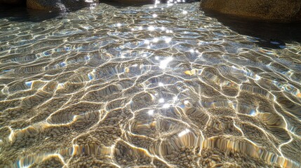 Sunlit Water Ripples Over Sandy Beach Under Clear Blue Sky