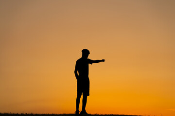 Silueta de chico apuntando hacia el horizonte 
