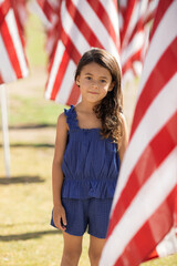 Little smiling girl standing next to American flag on 4th of July Day celebration