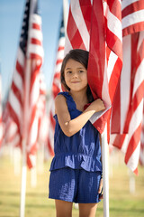 Smiling girl standing with American flag on 4th of July, Independence Day celebration
