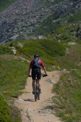 Experience mountain biking adventure! A cyclist conquers a rugged mountain trail under a bright...