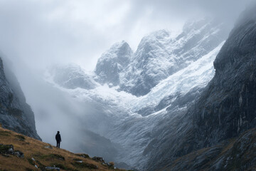 minimalist studio photograph of person on edge of glacial valley in peru soft gray background with light mist