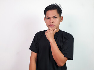 Portrait of Asian man in a black shirt placing hand on chin, expressing thoughtfulness and...