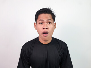 Portrait of a young man wearing a black shirt while displaying a surprised facial expression with...