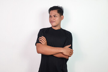 A confident Asian man stands against a plain white background, crossing his arms confidently. Ideal...