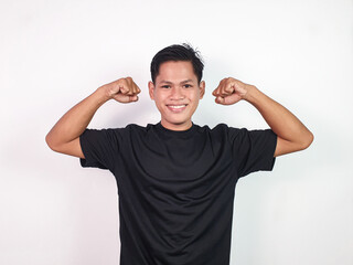 Fototapeta premium Smiling Young Asian Man Flexing His Strong Arms in a Confident Pose
