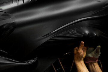 Matte black vinyl wrap application on front fender and wheel arch of luxury vehicle. Vinyl Wrapping...