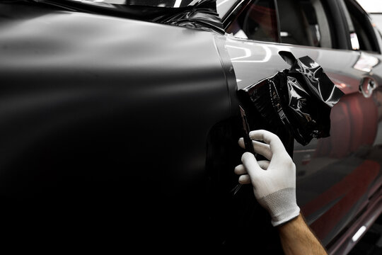 Trimming edges helps maintain clean finish. Vinyl edge cutting in detailing center. Applying wrap with precision cutters shapes vinyl. Clean cuts enhance aesthetics and prevent peeling.
