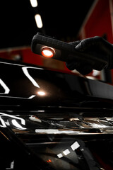 Swirl finder light to detect paint issues on black car in a detailing studio. Car Paint Inspection....