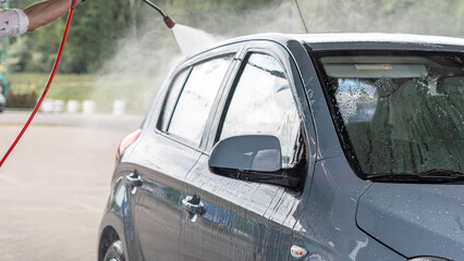 Car wash. Car cleaning foam soap bubbles. Spray water vehicle shine wet.
