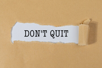The Text “DON’T QUIT” Appearing Behind Torn Brown Paper – Motivation & Resilience Concept