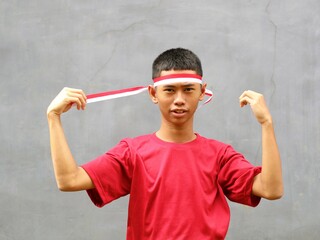 Indonesia boy in red shirt holding ribbon on his head, Indonesia independence day celebration...