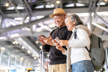 Senior asian couple sitting with luggage checking passport planning trip showing travel preparation...