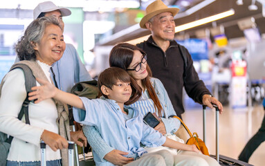 Asian multigenerational family at airport traveling with kids and grandparents, joyful moments of...