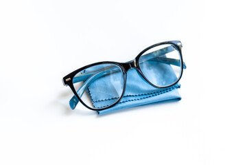 Stylish eyeglasses with glasses cloth on white. Eye care and protection concept