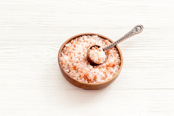 Coarse pink salt in wooden bowl and spoon and spilled salt. Cooking or spa concept