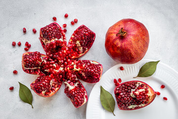 Top view of fresh ripe pomegranate and pieces on plate for eating, top view.