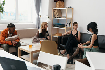 group of young adult colleagues socializing in casual workplace with coworkers and friends...