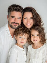 Fototapeta premium Beautiful family with two young children poses together indoors, smiling and embracing with love and happiness.