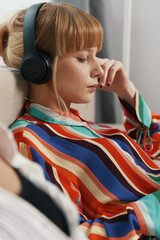 Young adult woman listening to music with headphones, relaxing and socializing in a casual...