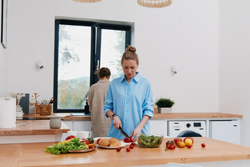 middle age woman preparing healthy food in kitchen with fresh vegetables, promoting active and healthy lifestyle, wellbeing, and fitness indoors