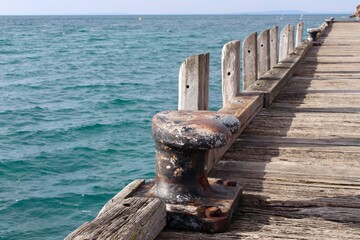 Weathered wooden pier and iron mooring stretch to the horizon, set against the turquoise ocean.