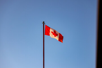 Canada Flag flagging in a withstand with blue sky in the background