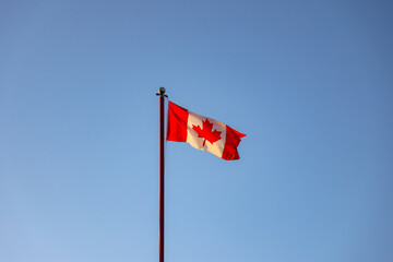 Canada Flag flagging in a withstand with blue sky in the background
