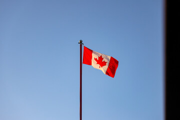 Canada Flag flagging in a withstand with blue sky in the background