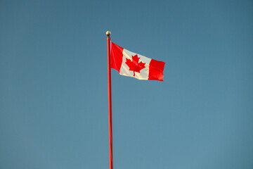Canada Flag flagging in a withstand with blue sky in the background