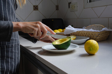 Woman's hands preparing avocado with lemon and salt in the kitchen.