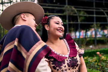 Portrait of a smiling young couple, dressed as Chilean huasos, posing romantically, about to kiss...