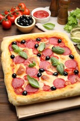 Tasty homemade pizza and ingredients on wooden table