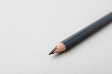 Grey eyebrow pencil on light background, closeup. Space for text