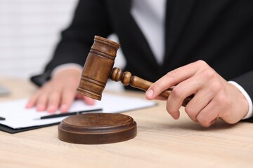Judge with gavel working at desk indoors, closeup