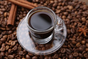 Cup with aromatic coffee, star anise and cinnamon on beans, closeup