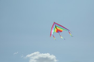 Colorful kite flying in blue sky, low angle view. Space for text