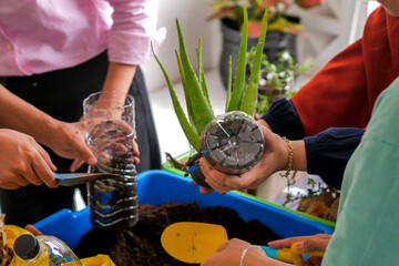 Close Up Of Group Engaged In Environmental Project Repurposing Bottles For Plants