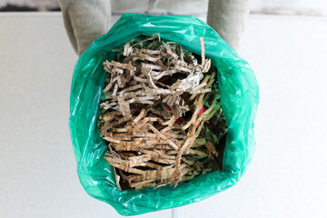 Top View Of Hands Presenting Green Bag Filled With Shredded Cardboard